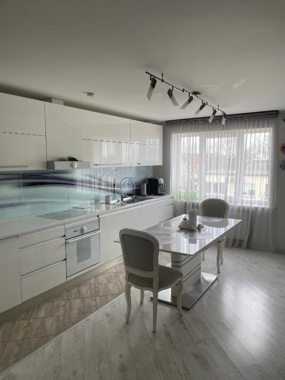 een witte keuken met een tafel en stoelen. bij Emporium Apartments in Rēzekne