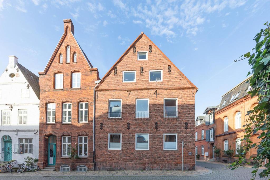an old brick building with white windows on a street at Ankerliebe in Husum