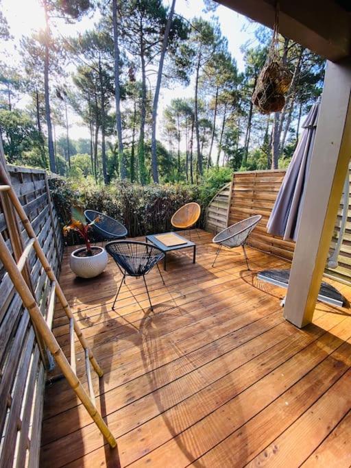 une terrasse en bois avec des chaises et un banc. dans l'établissement Le calme entre plage (700m) et golf! (Classé 3*), à Seignosse
