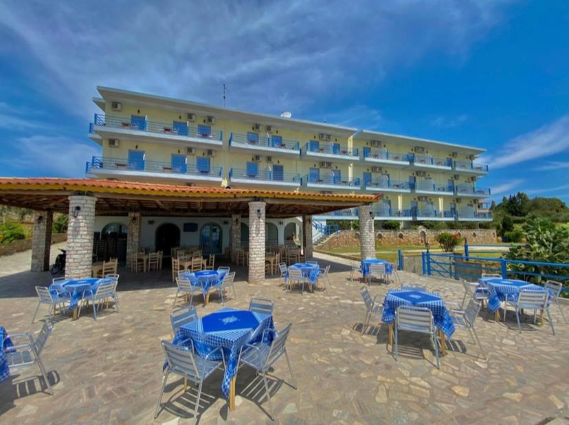 コロニにあるDe La Plage Hotel Koroniのホテルの前に青いテーブルと椅子があります。