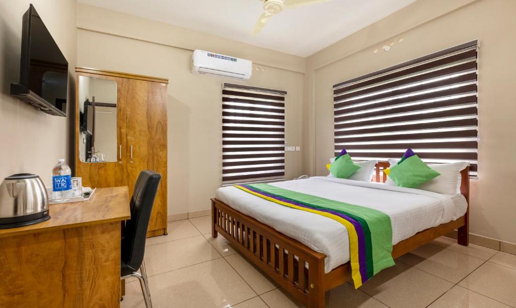a bedroom with a bed and a desk and a television at Treebo Trend Dreams Arcade in Angamali
