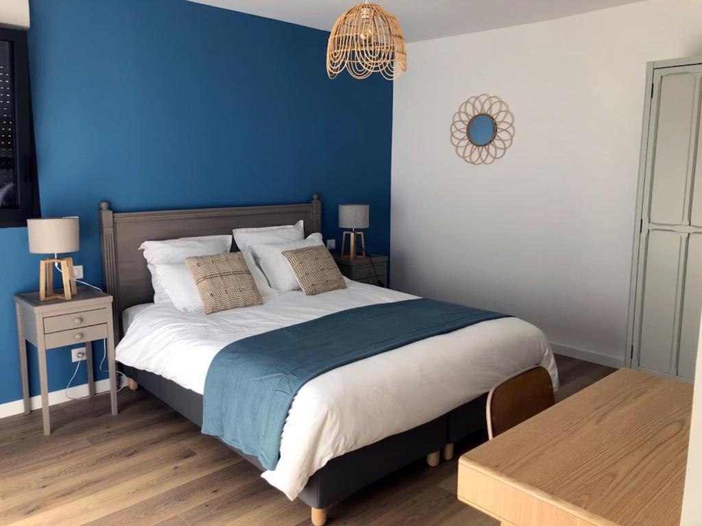 een slaapkamer met een groot bed met een blauwe muur bij Gîtes de Lauvergnac - Maisons 2 Ch, 2 SdB in La Turballe