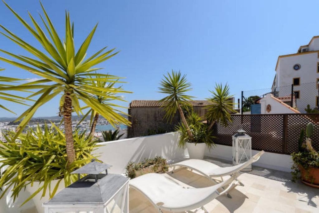 a balcony with two white chairs and a palm tree at Dalt Vila House in Ibiza Town