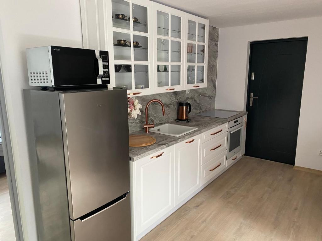 uma cozinha com um frigorífico de aço inoxidável e armários brancos em Mega widok 2 em Szklarska Poręba