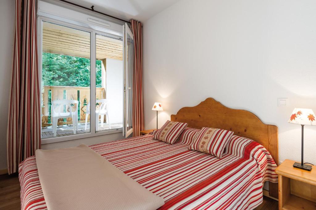 1 dormitorio con cama y ventana grande en Lagrange Vacances Le Domaine des 100 Lacs en Cauterets