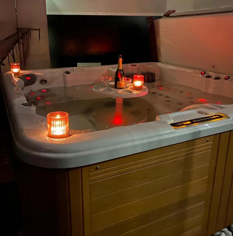 a hot tub with candles and a bottle of champagne at La Villa Audren Love Room Jacuzzi in Châtelaudren
