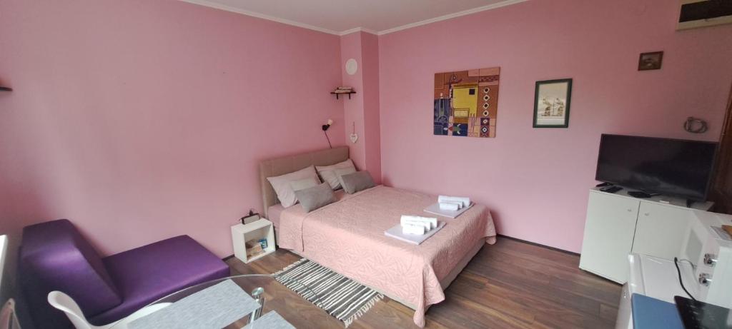 um pequeno quarto rosa com uma cama e uma cadeira em Apartmani Krcmarica 10 em Divčibare