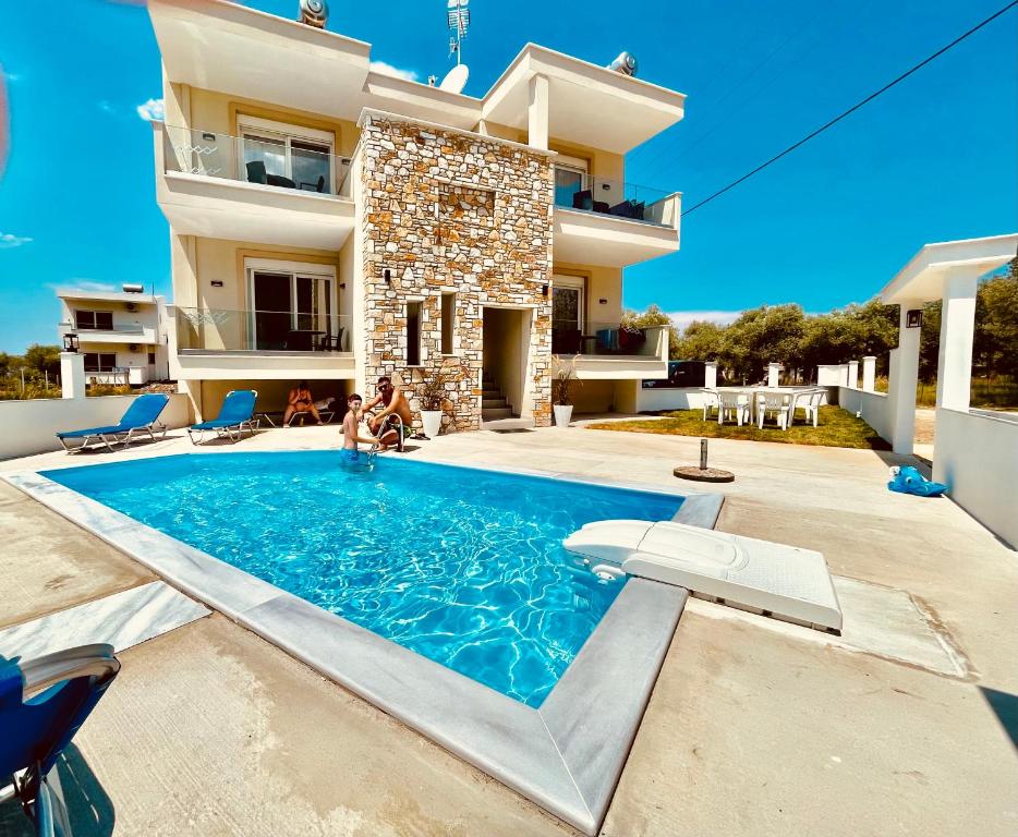 a villa with a swimming pool in front of a house at Green Memories in Skala Sotiros