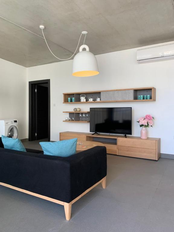 een woonkamer met een zwarte bank en een flatscreen-tv bij Village Point Apartments in Sliema