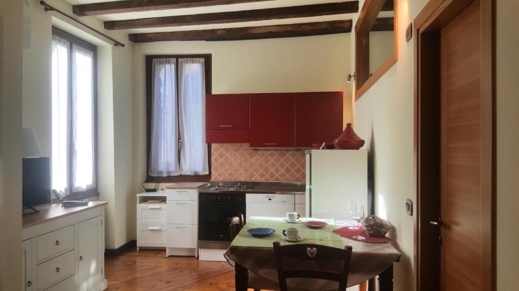 ヴェローナにあるMonolocale in Centro a Veronaのテーブル付きのキッチン、赤いキャビネット付きのキッチン