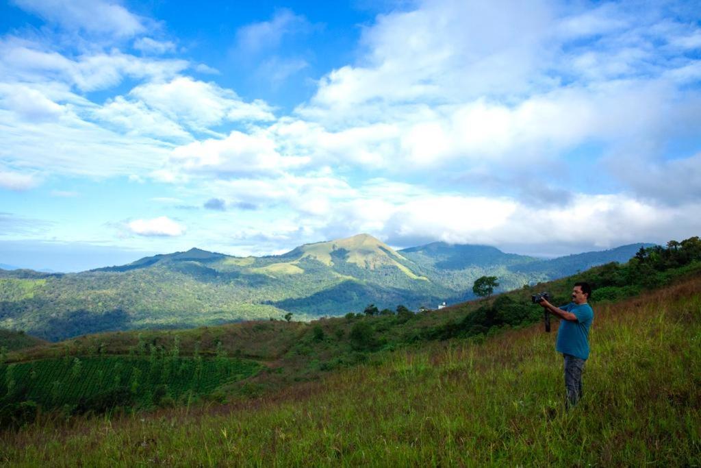 Un uomo in piedi su una collina che guarda le montagne di The Forest Resort - Muneeswaramudi Eco Hermitage and Farms a Tindummal