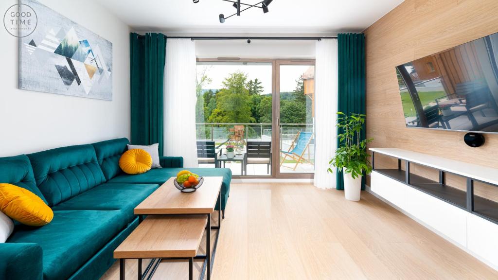 een woonkamer met een groene bank en een tafel bij Apartamenty Good Time- Stone Hill II in Szklarska Poręba