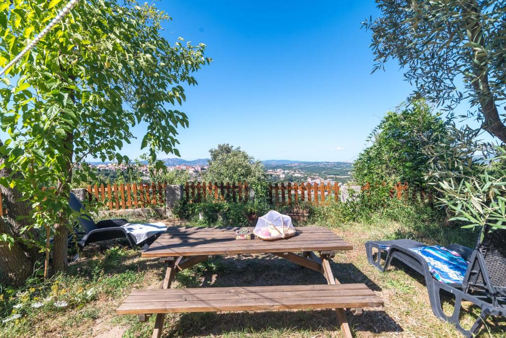 una mesa de picnic de madera en un jardín con vistas en Home on the hill en Tempio Pausania