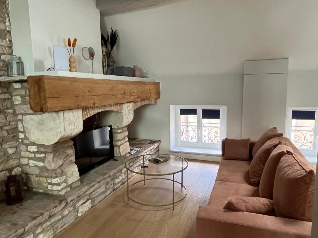 ein Wohnzimmer mit einem Sofa und einem Kamin in der Unterkunft Clos Théodore - Appartement climatisé avec sauna, petite terrasse et mezzanine in Givry