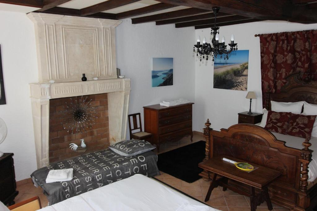 a bedroom with a bed and a fireplace at La Charentaise des Lilas in Saint-Léger