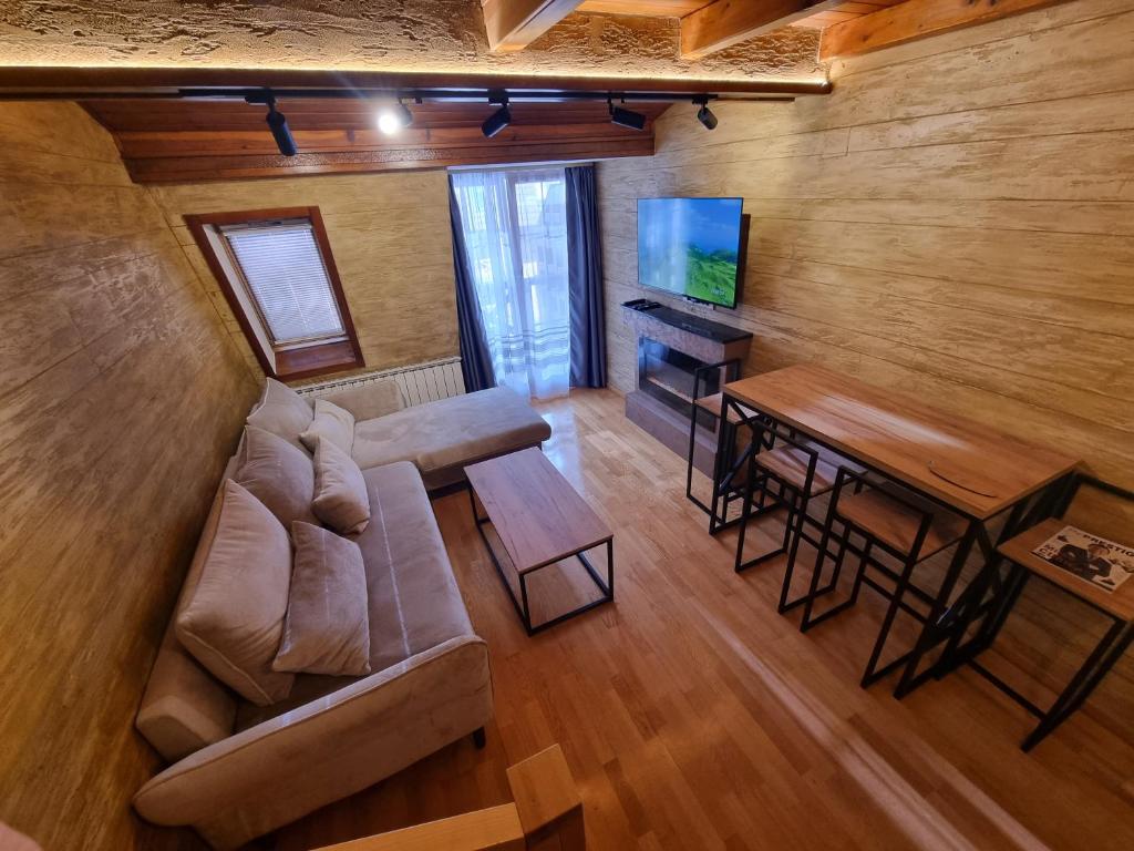 een woonkamer met een bank, een tafel en een televisie bij Apartman Lord Aparthotel Vučko in Jahorina