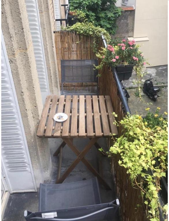 une table et une chaise en bois sur une terrasse fleurie dans l'établissement Charmant appartement à Montmartre, à Paris