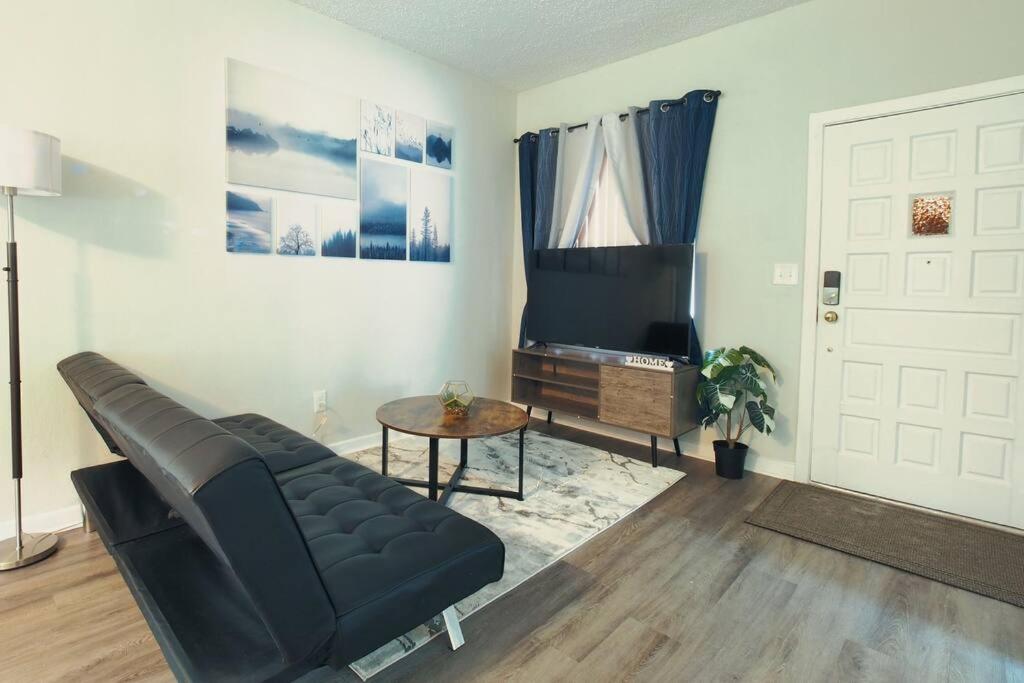 a living room with a black couch and a television at Spacious Modern 5 Bedrooms JAX in Jacksonville
