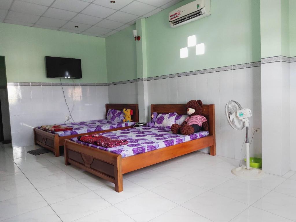 1 dormitorio con 2 camas y un osito de peluche en Nhà nghỉ Kim Vân, en Soc Trang
