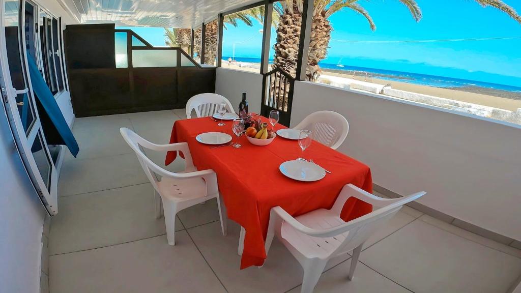 a dining room with a red table and white chairs at Apartamento Tierra, Primera línea Mar in Playa Honda