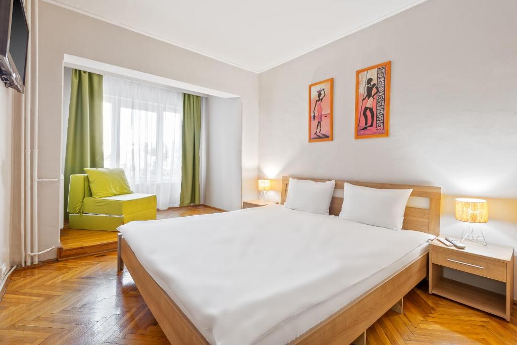 ein Schlafzimmer mit einem großen Bett und einem gelben Stuhl in der Unterkunft Apartament Helena in Oradea