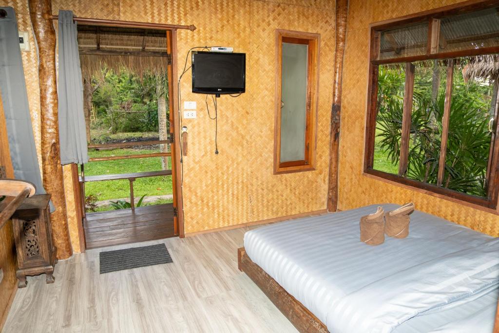 a bedroom with a bed with a tv and a window at Butterfly Hostel, Pai in Pai