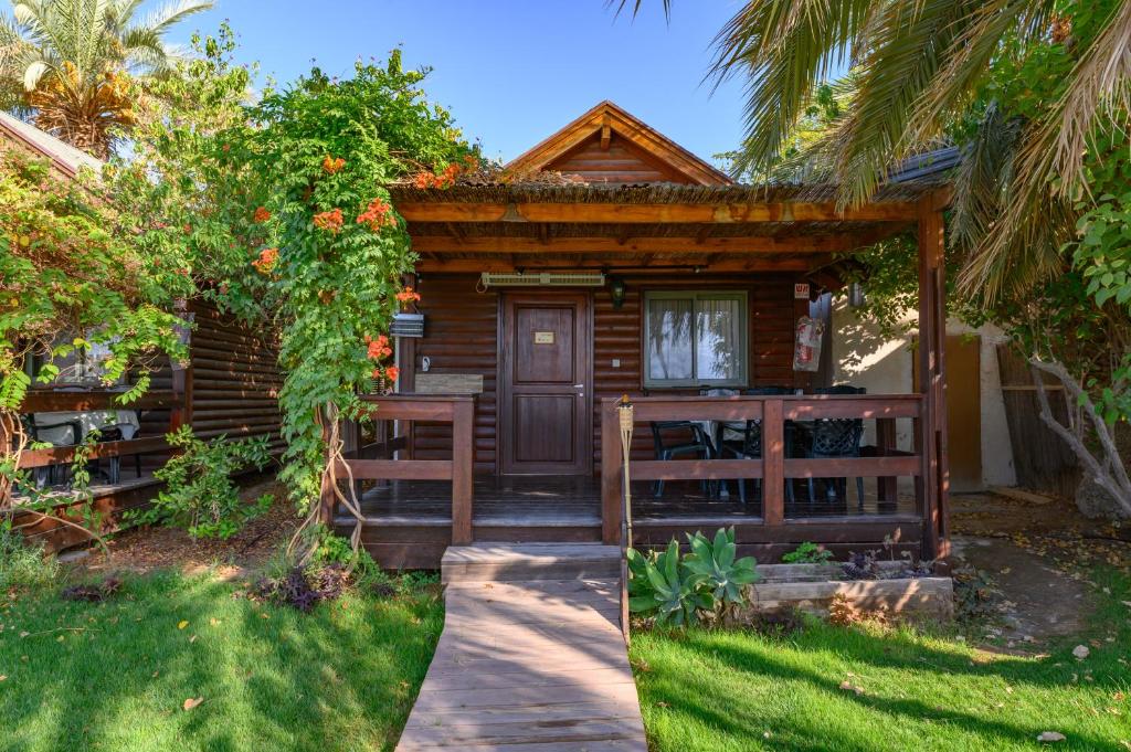 a wooden cabin with a pathway leading to the front door at Belfer's Dead Sea Cabins in Neʼot HaKikar