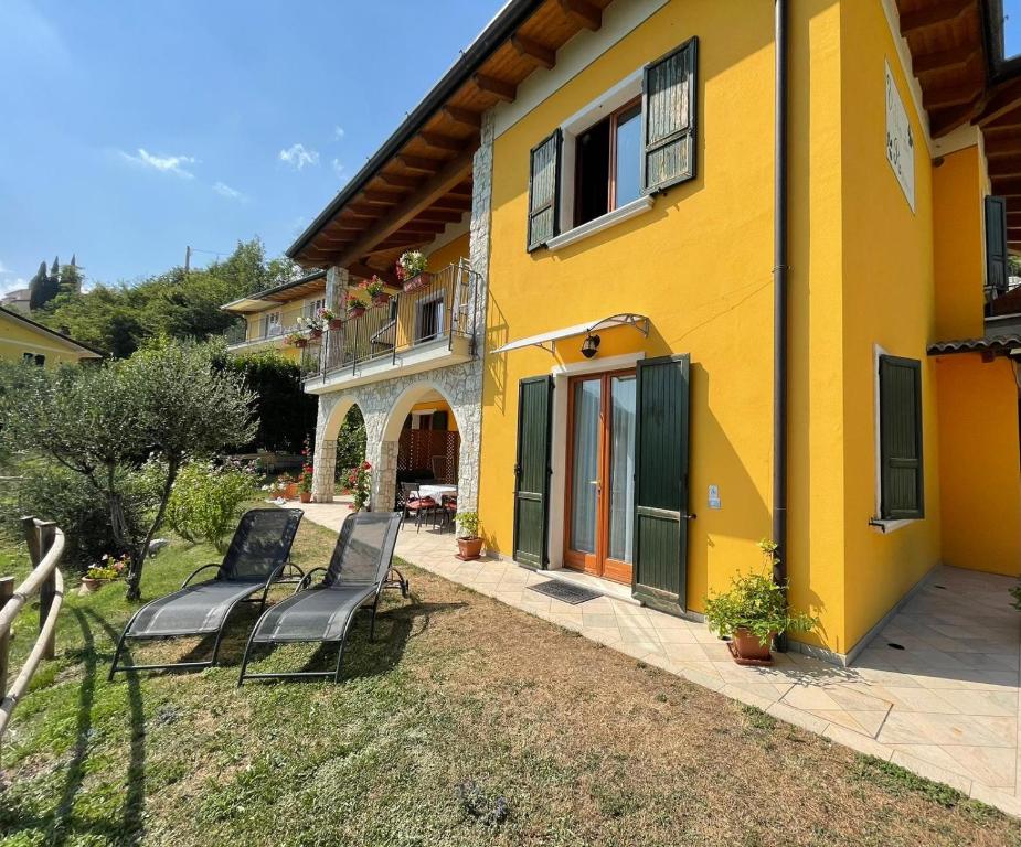 ein gelbes Haus mit zwei Stühlen davor in der Unterkunft Villa dei Roveri in Tignale
