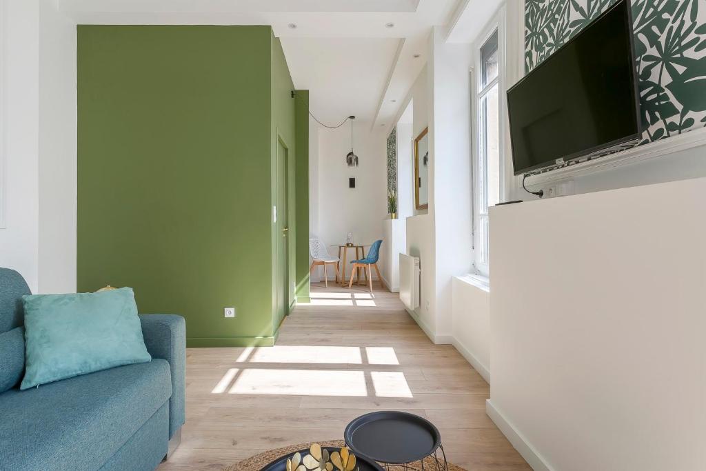 un salon avec un canapé bleu et une télévision à écran plat dans l'établissement Magnifique Studio - Lyon 3, à Lyon