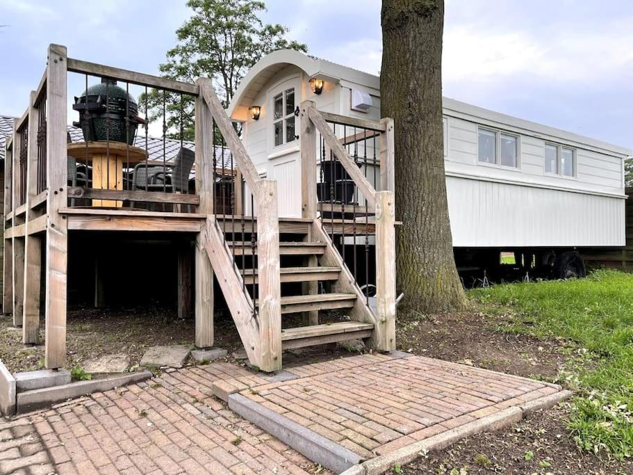 a house with a wooden staircase next to a tree at Natuurhuisje Markelo, zeer compleet, met veel luxe in Markelo