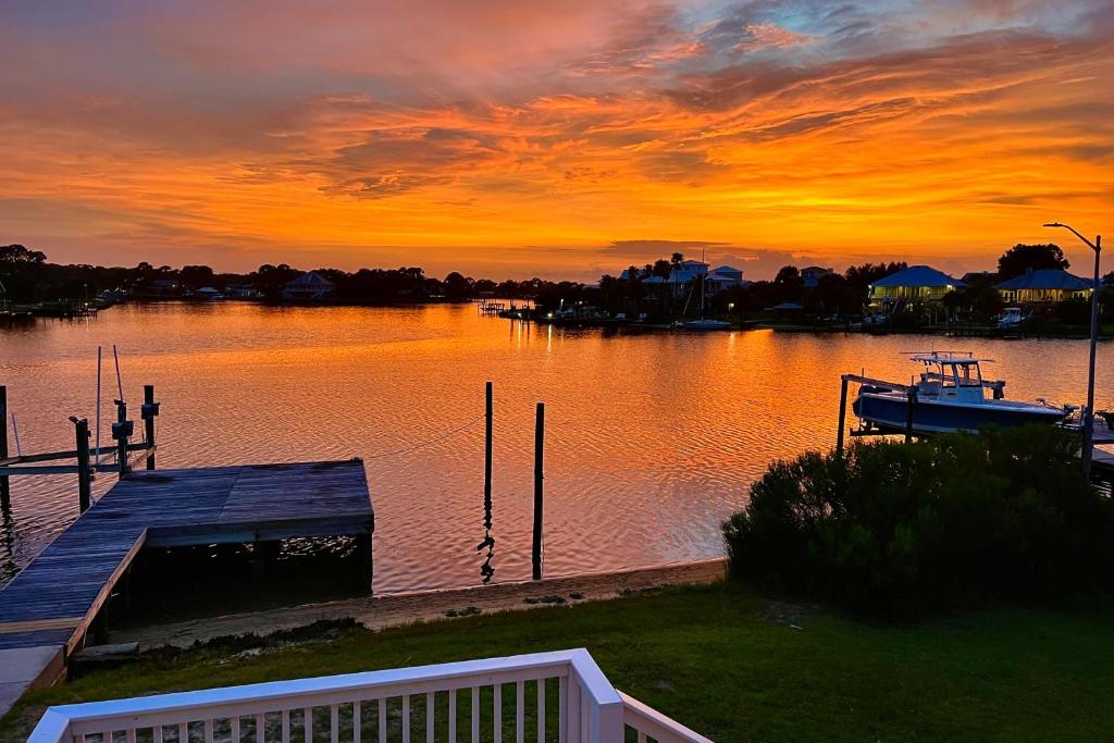 a sunset over a body of water with a dock at Sunset Bay in Dauphin Island