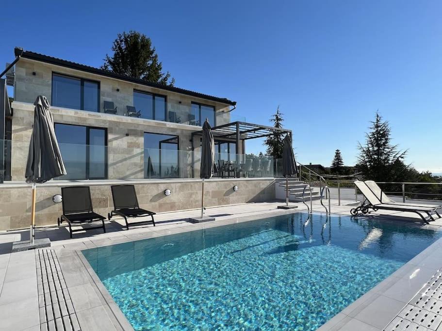 a swimming pool with two chairs and a house at Villa Balchik in Balchik