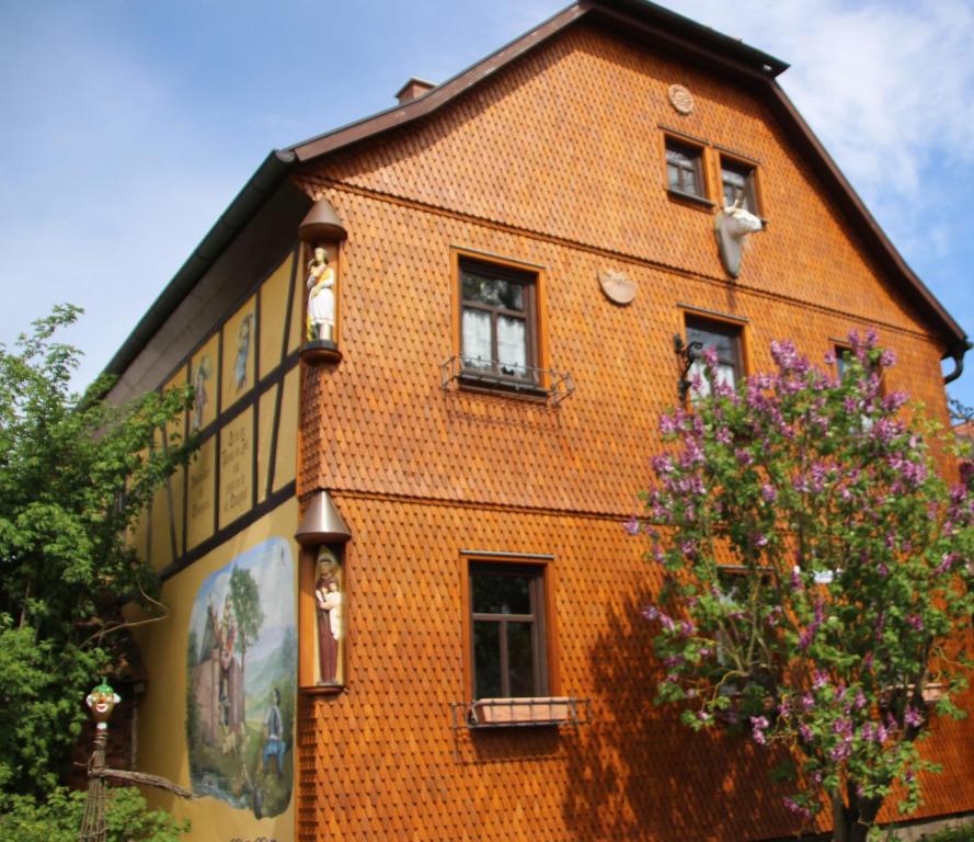 an orange brick building with windows and a tree at Pension Rhöner Kräuterwerk 