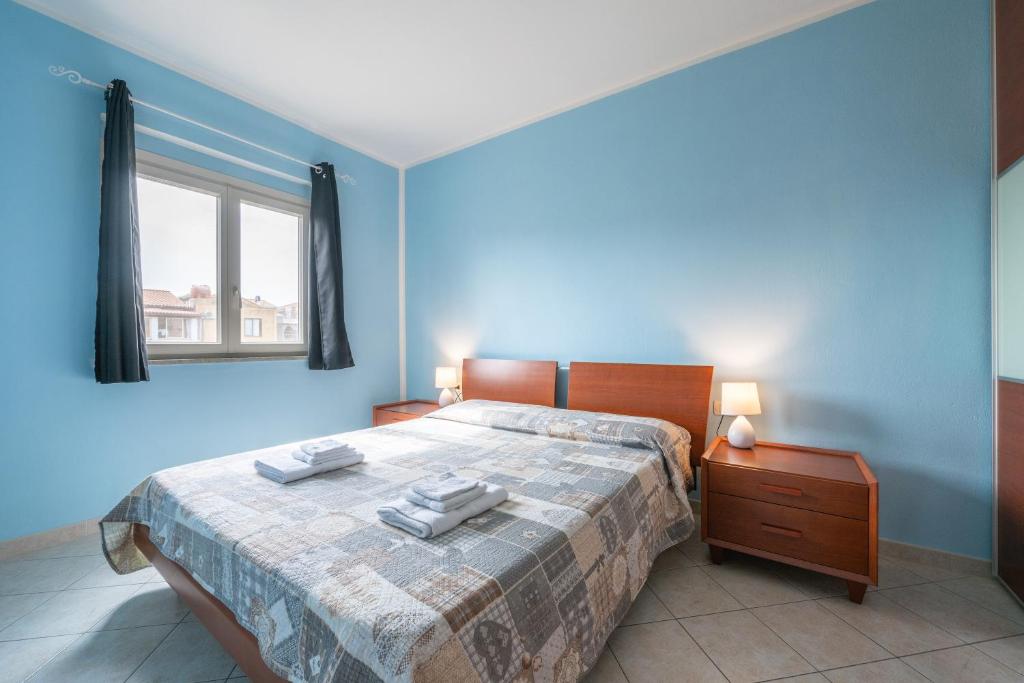 niebieska sypialnia z łóżkiem z dwoma ręcznikami w obiekcie Casa Murru w mieście SantʼAntìoco
