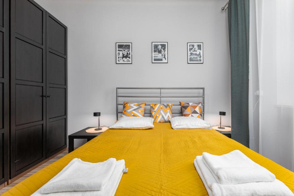 a bedroom with a large yellow bed with two pillows at Siewierska 17 by Homeprime in Warsaw