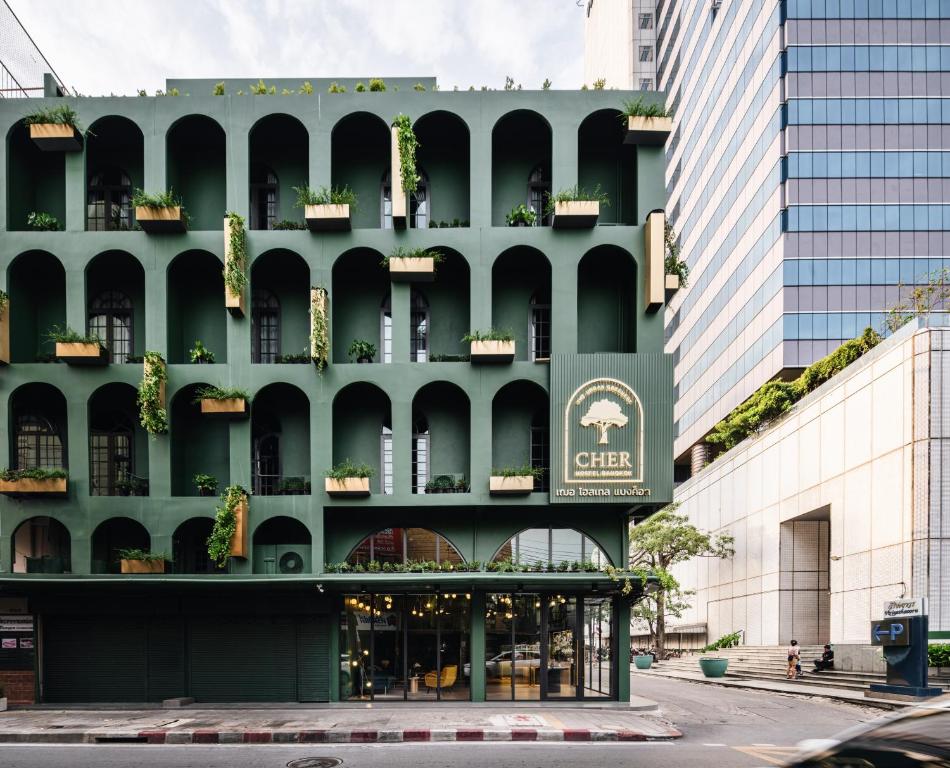 a green building with a sign on the side of it at Cher Hostel Bangkok in Bangkok