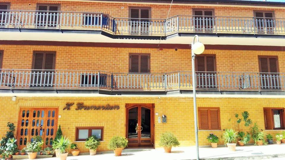 un edificio in mattoni gialli con balconi e piante di Albergo Grumentum a Grumento Nova