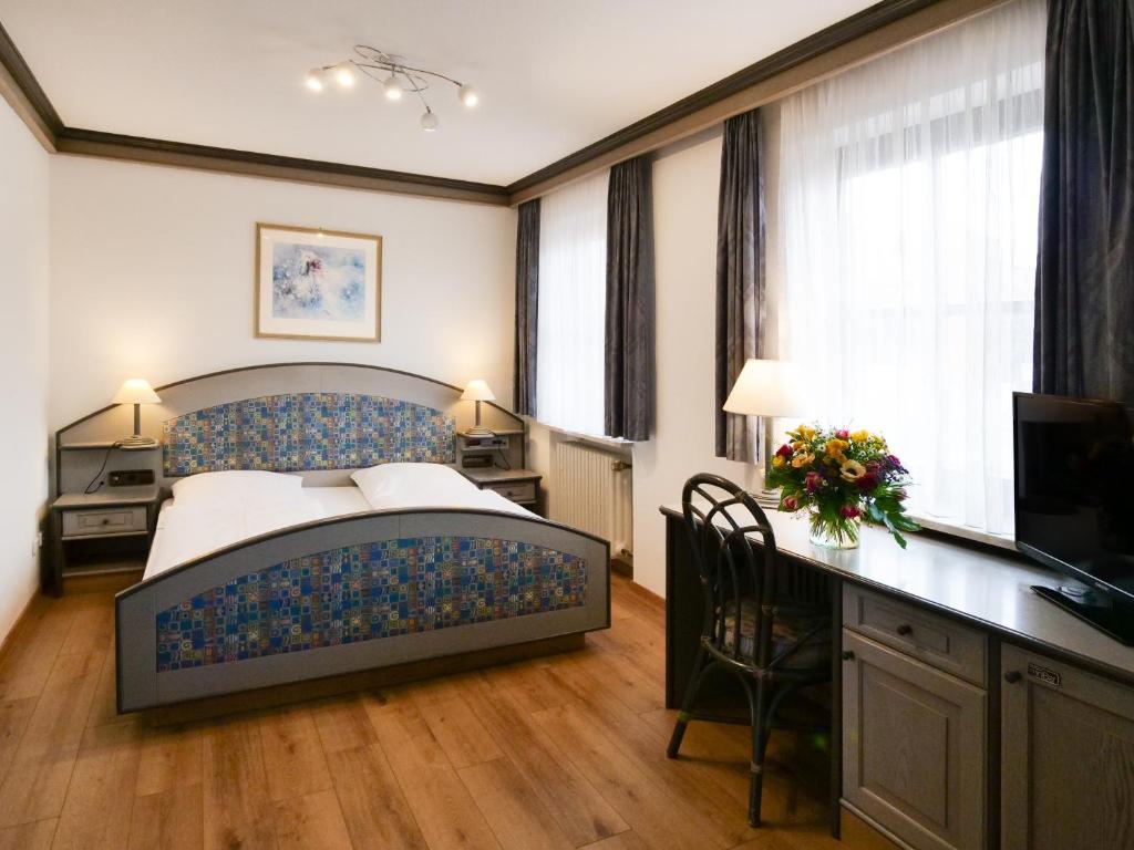 sypialnia z łóżkiem, biurkiem i telewizorem w obiekcie Seehotel Pegasus w mieście Herrsching am Ammersee
