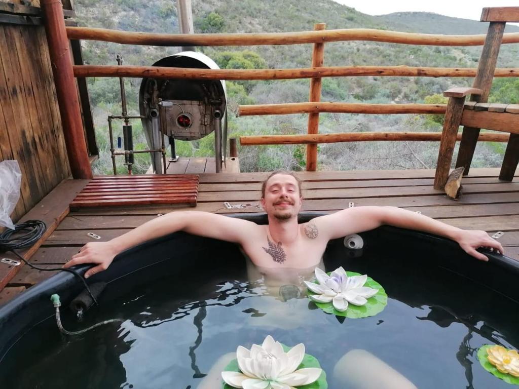 Ein Mann in einer Badewanne mit Seerosen in der Unterkunft Protea Lodge - Glamping in the Karoo in Barrydale