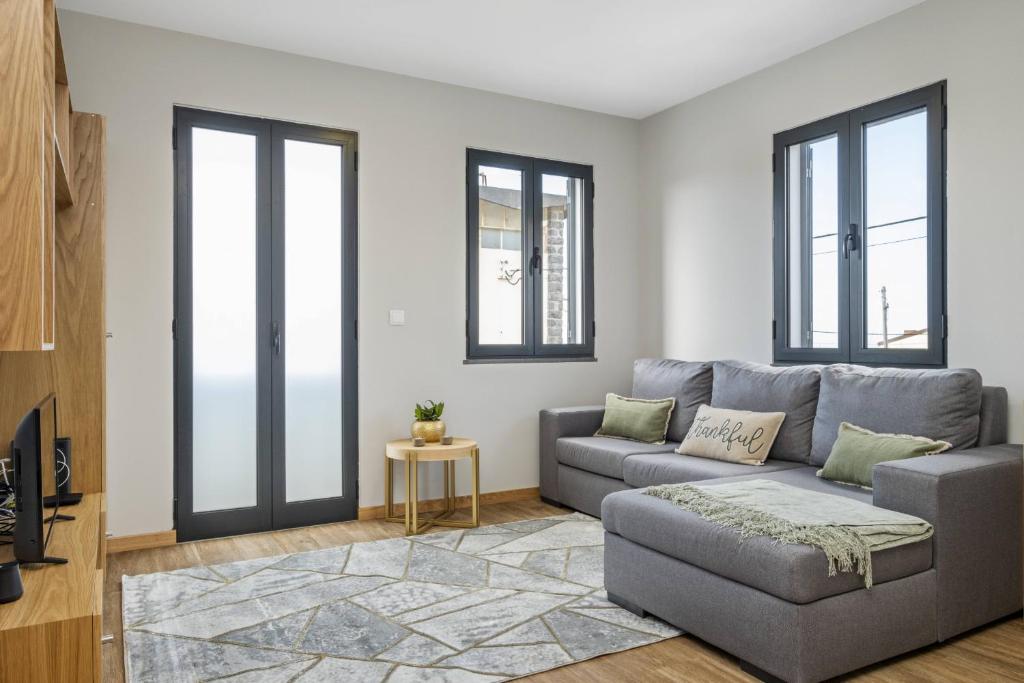 a living room with a gray couch and windows at Salsa Country House II by Madeira Sun Travel in Porto Moniz