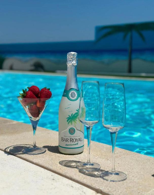 three wine glasses and a bottle of champagne next to a pool at Alto do Moinho in Alcobaça