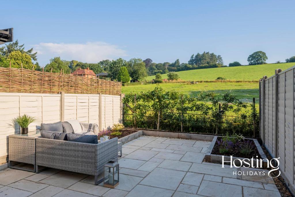 a patio with a couch and a fence at Cosy Countryside Cottage With Incredible Views in Henley on Thames