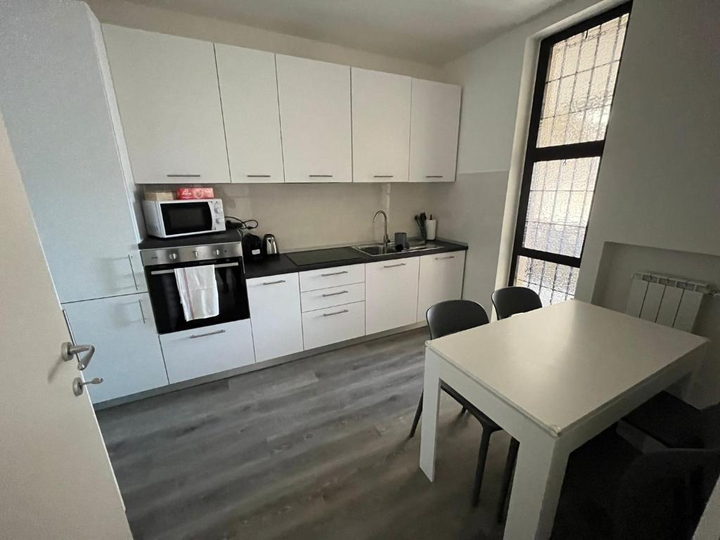a kitchen with white cabinets and a table and a microwave at Dream Baveno 2 in Baveno