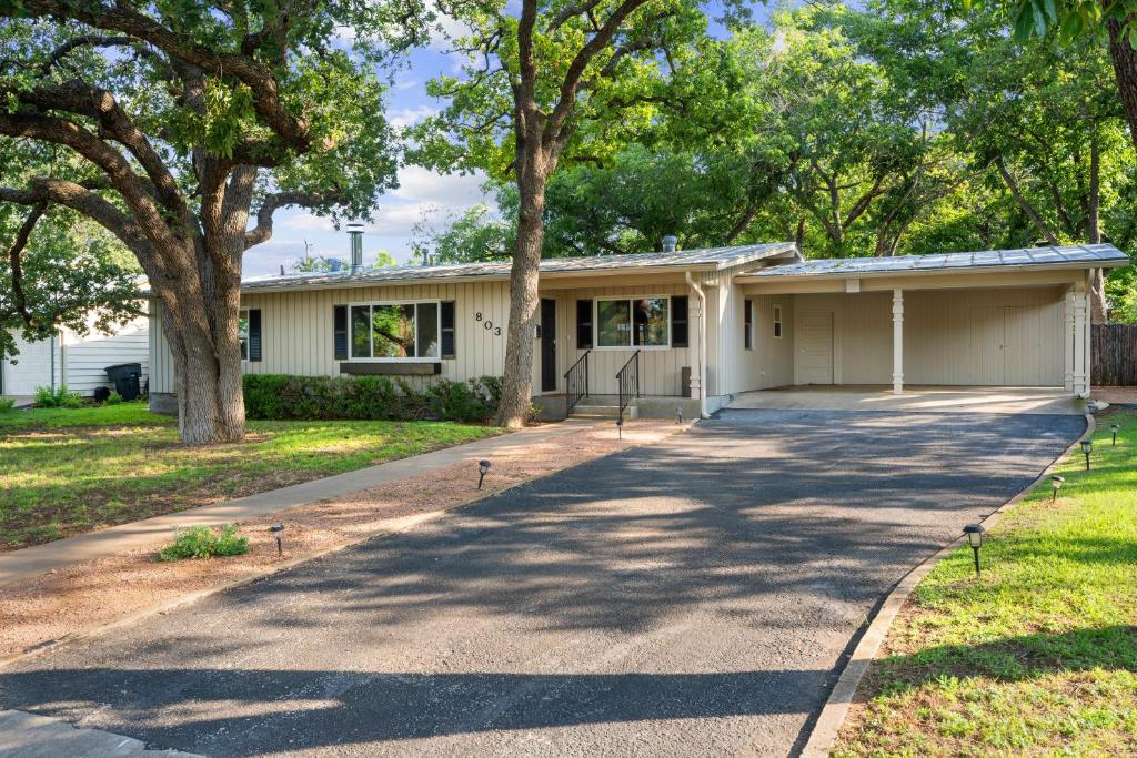 a white house with trees in front of it at Backyard Oasis w/Pool, Hot-Tub, Grill & Fire Pit! in Fredericksburg
