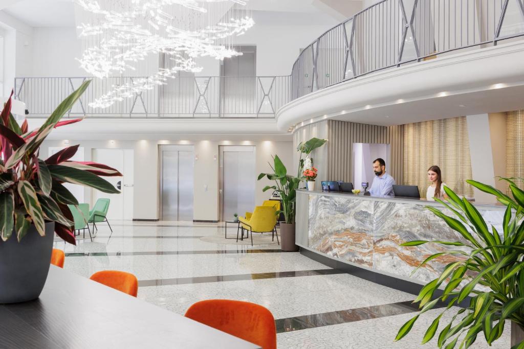 two people in an office lobby with plants at IH Hotels Milano Centrale in Milan