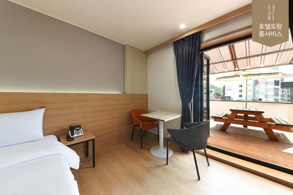 a bedroom with a bed and a desk and a window at Hotel Torang Jeonju in Jeonju