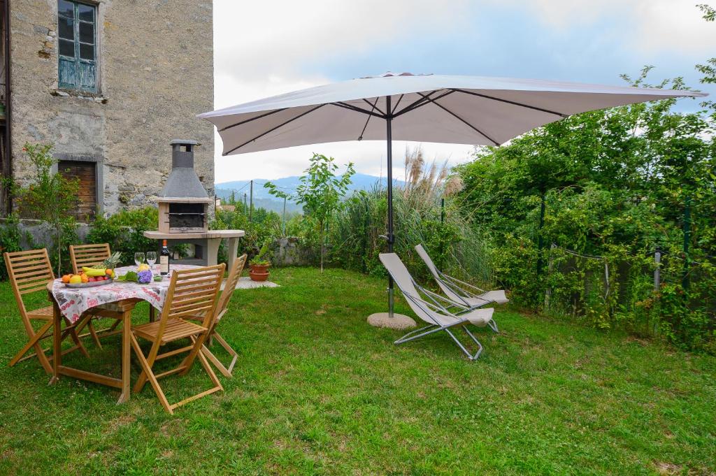 un tavolo e sedie con ombrellone in un cortile di La casa di Leo a Riccò del Golfo di Spezia