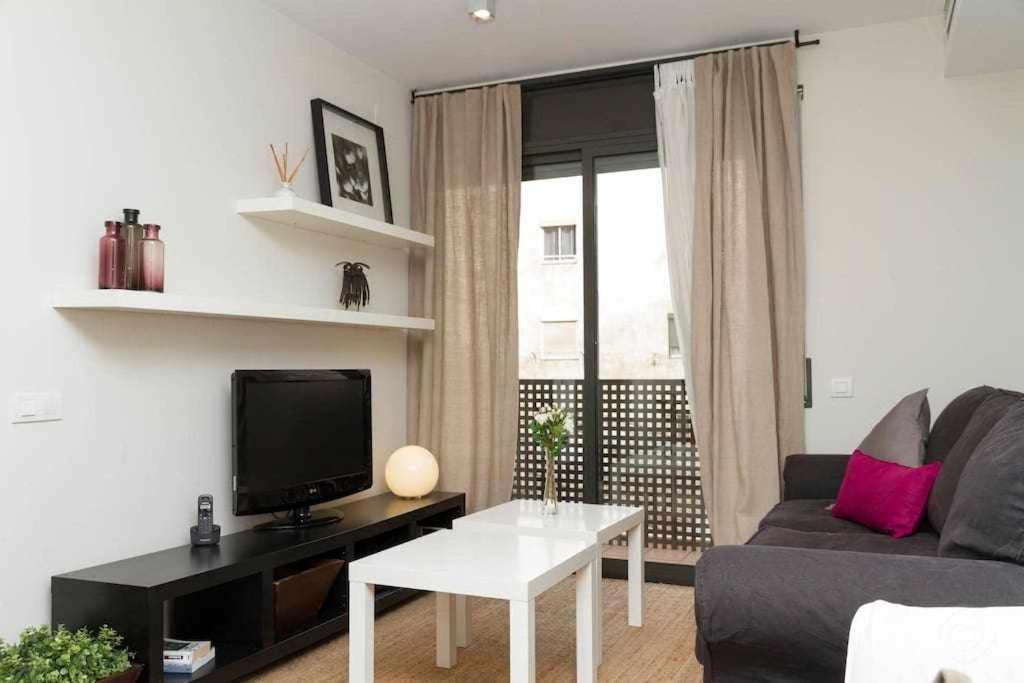 ein Wohnzimmer mit einem Sofa und einem TV in der Unterkunft Port III Apart céntrico ideal familias 11 in Barcelona