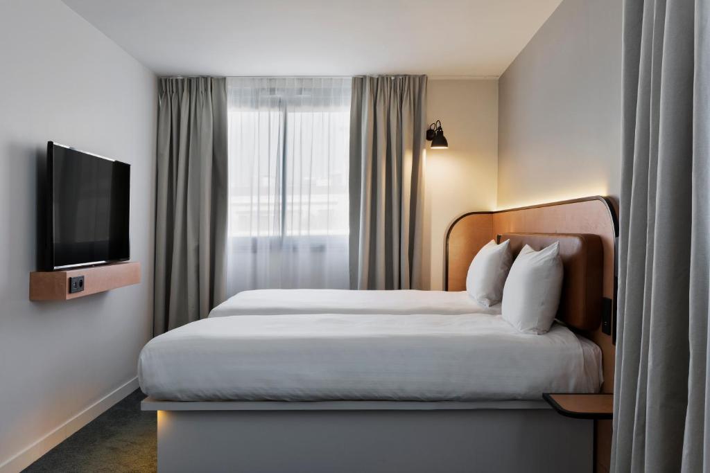 a hotel room with a bed and a flat screen tv at Moxy Paris Bastille in Paris