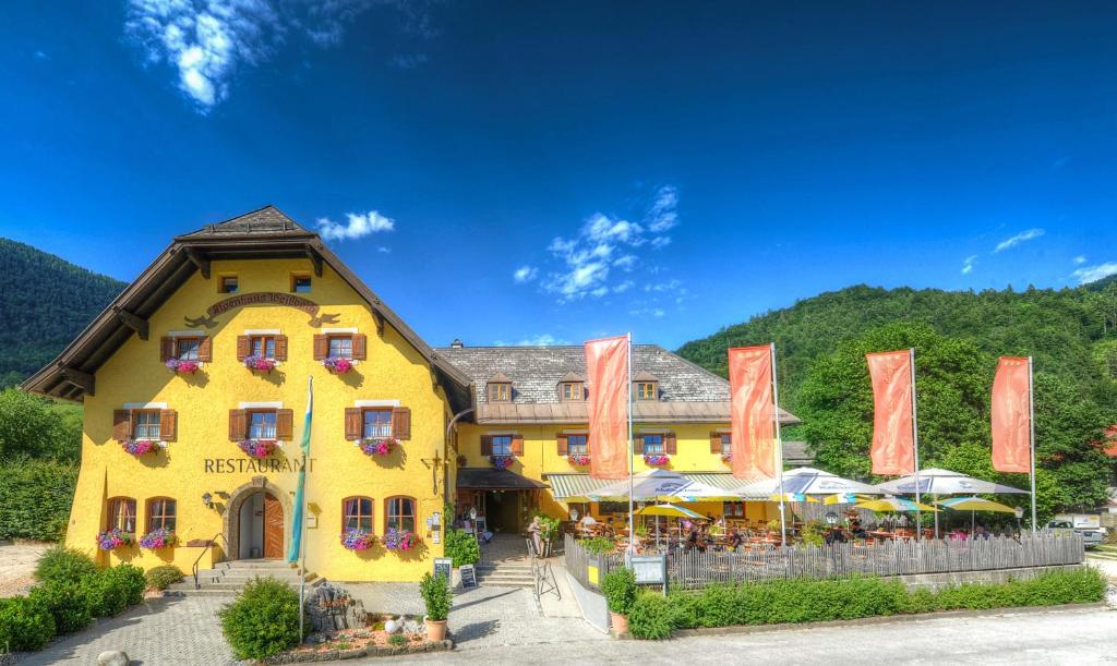 a yellow building with orange flags in front of it at DEVA Hotel Alpenglück in Weißbach